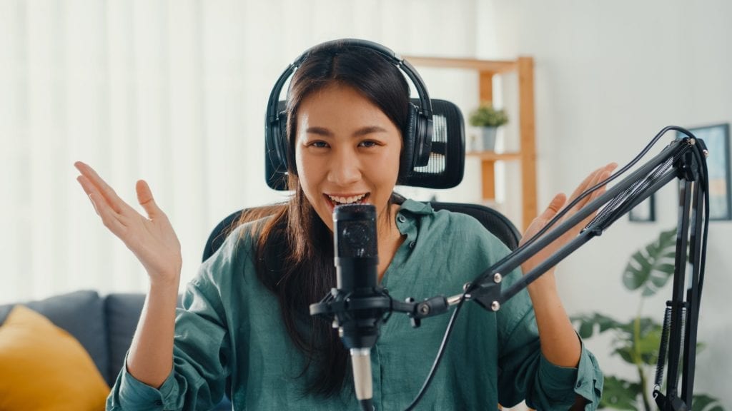 Happy asia girl record a podcast with headphones and microphone look at camera talk and take.