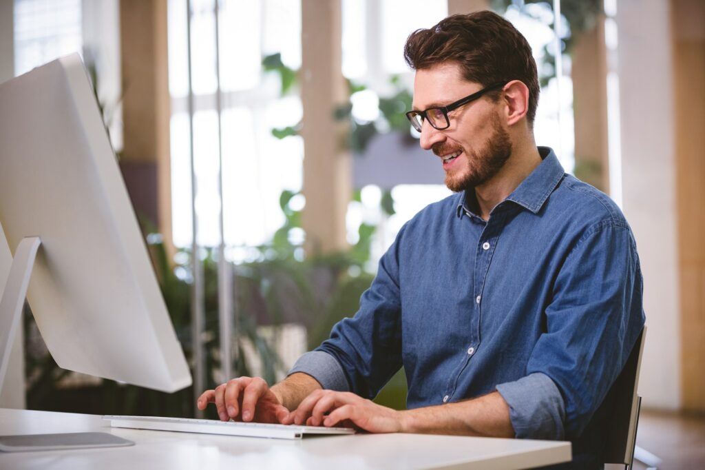 Happy businessman working on computer at creative office