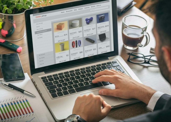 Online shop website developer working with a laptop, office desk background.